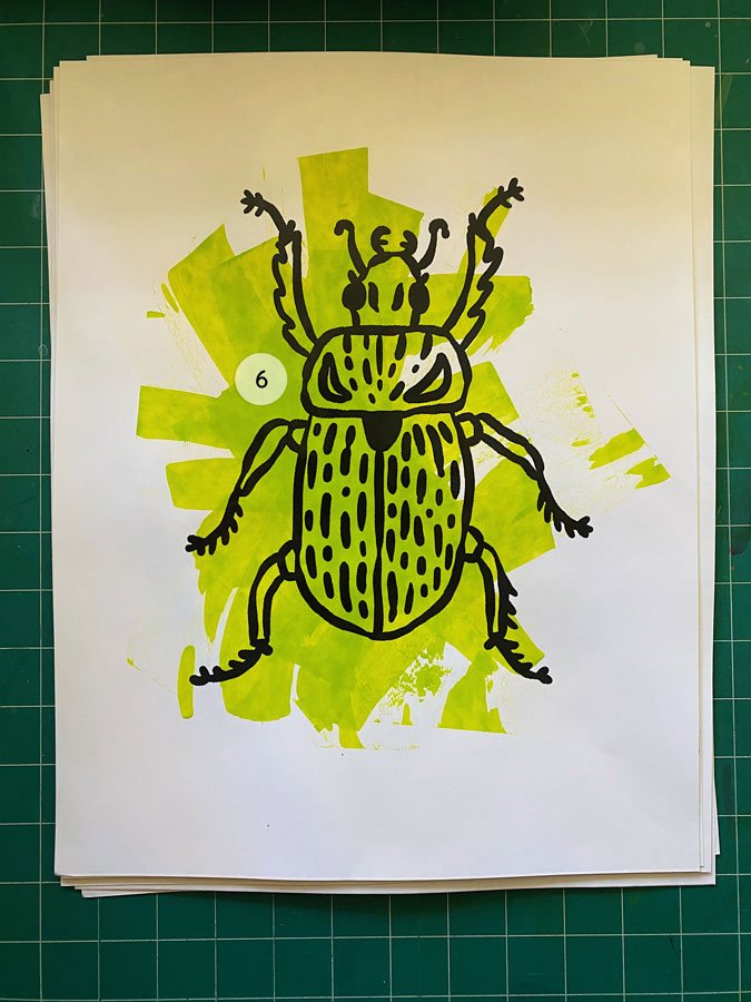 Overview of a hand made 11"x14" screen print of a beetle with a colorful lime green paint swipe background.