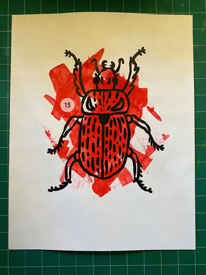 Overview of a hand made 11"x14" screen print of a beetle with a colorful red paint swipe background.