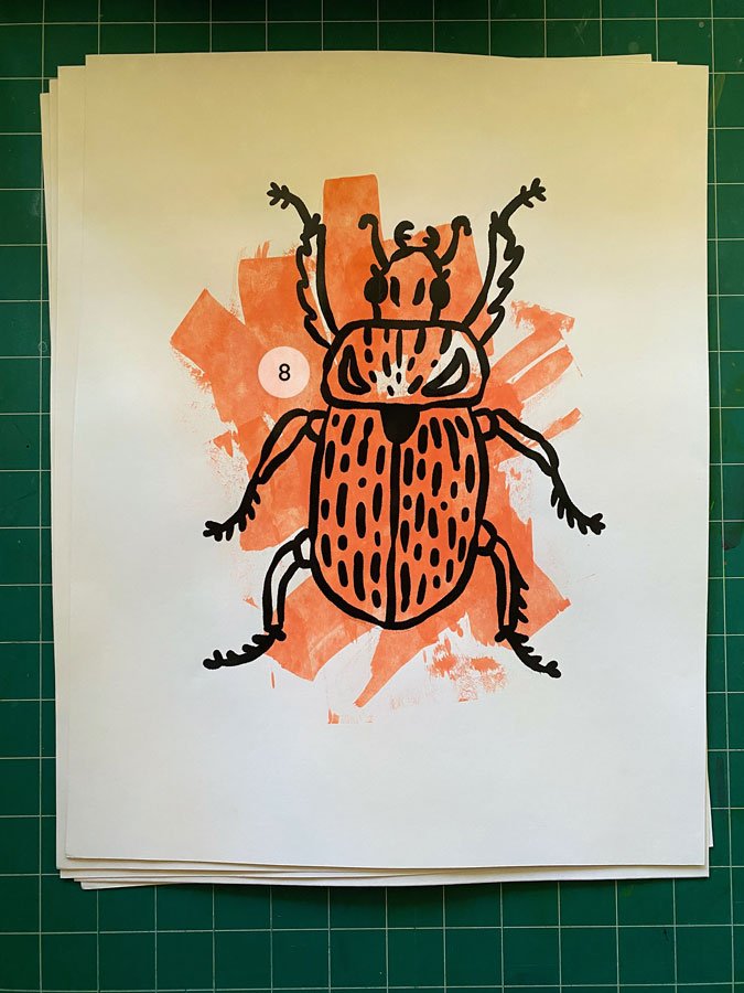 Overview of a hand made 11"x14" screen print of a beetle with a colorful coral paint swipe background.