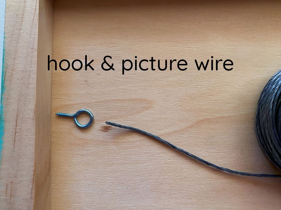 Photo of the back of the wooden panel with hooks and wire hanger option.