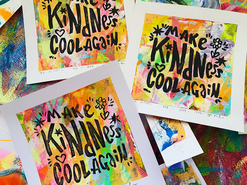 Group photo of lino cut prints with a hand-painted backing and text that reads "make kindness cool again".