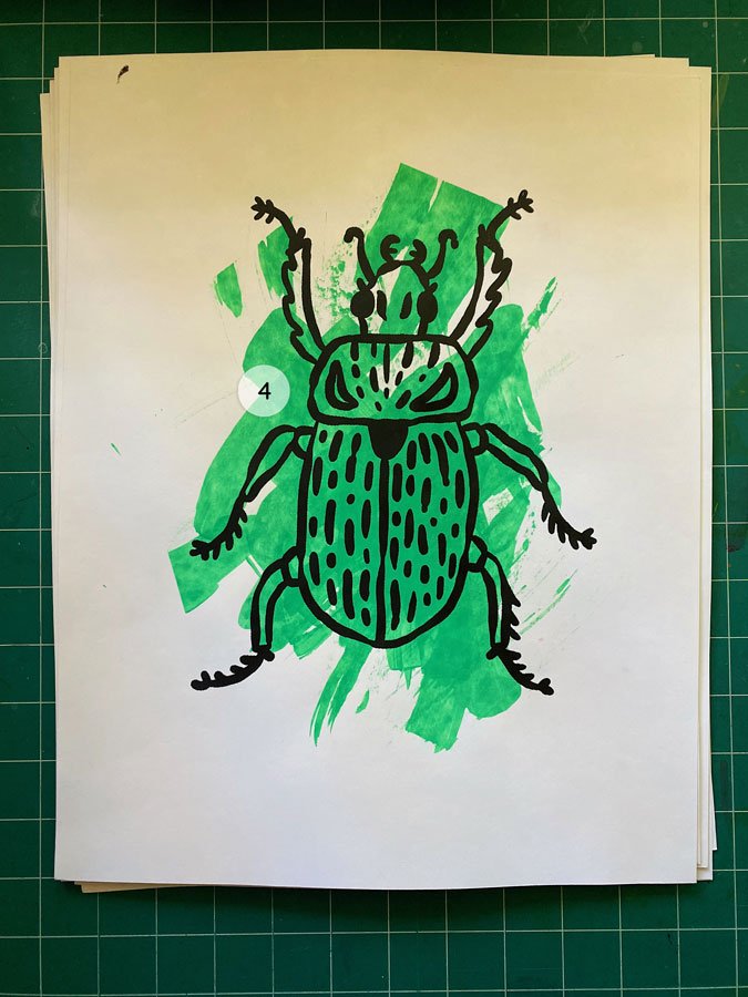 Overview of a hand made 11"x14" screen print of a beetle with a colorful emerald green paint swipe background.
