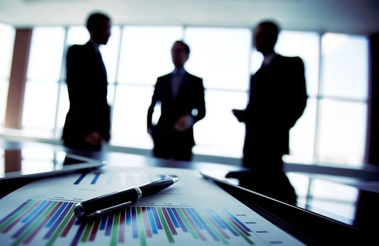 Silhouetted business professionals in discussion at a conference table with large windows in the background — cover art for The Monday Friday War