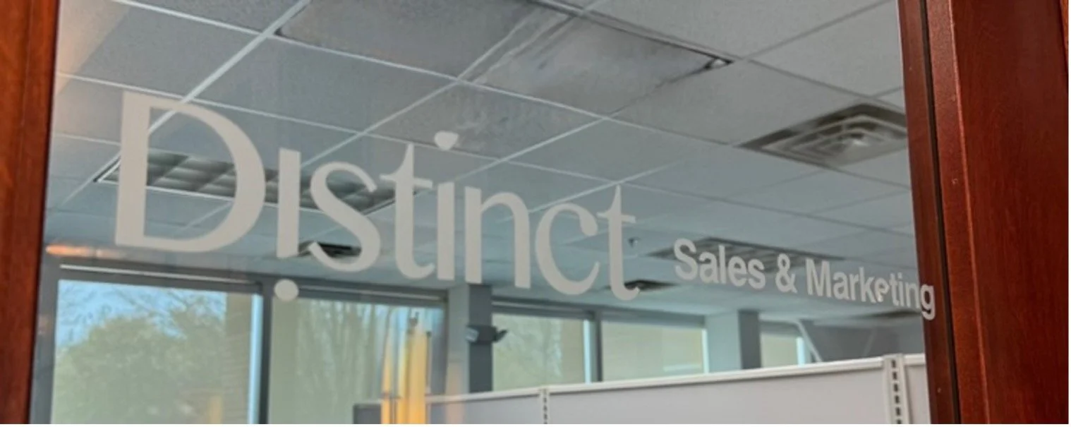 Office window decal with the words 'District Sales & Marketing' in large white letters.