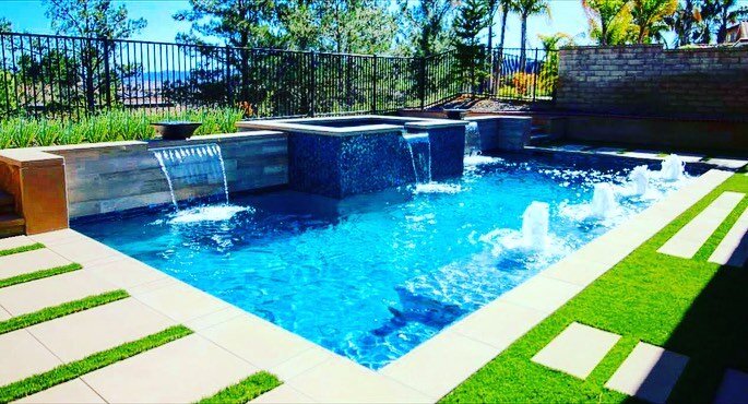 Who is ready for summer?! We know we are and can&rsquo;t wait for some relaxation and quality time in and by the pool. || #throwbackthursday || This backyard pool oasis with a water feature, sheer descents, mosaic glass tile, and fire bowls left our 
