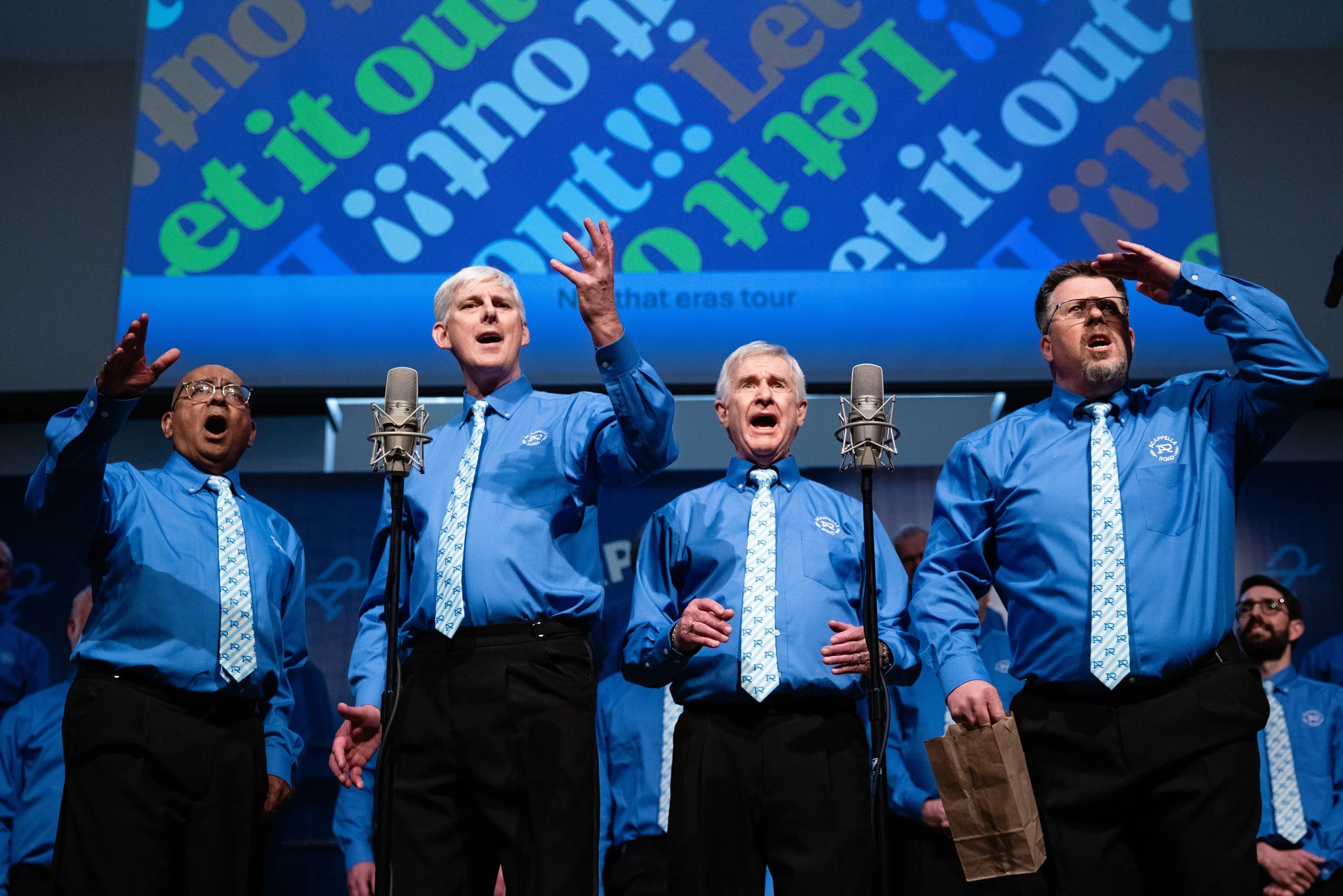 Sound Advice, a four-man barbershop quartet, performing onstage in blue shirts and patterned ties.