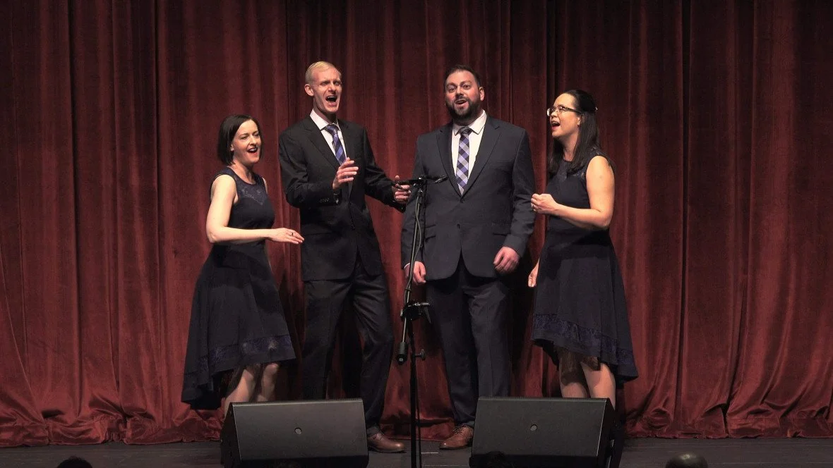 Alloy, a two-man and two-woman barbershop quartet, performing onstage in black formal attire.