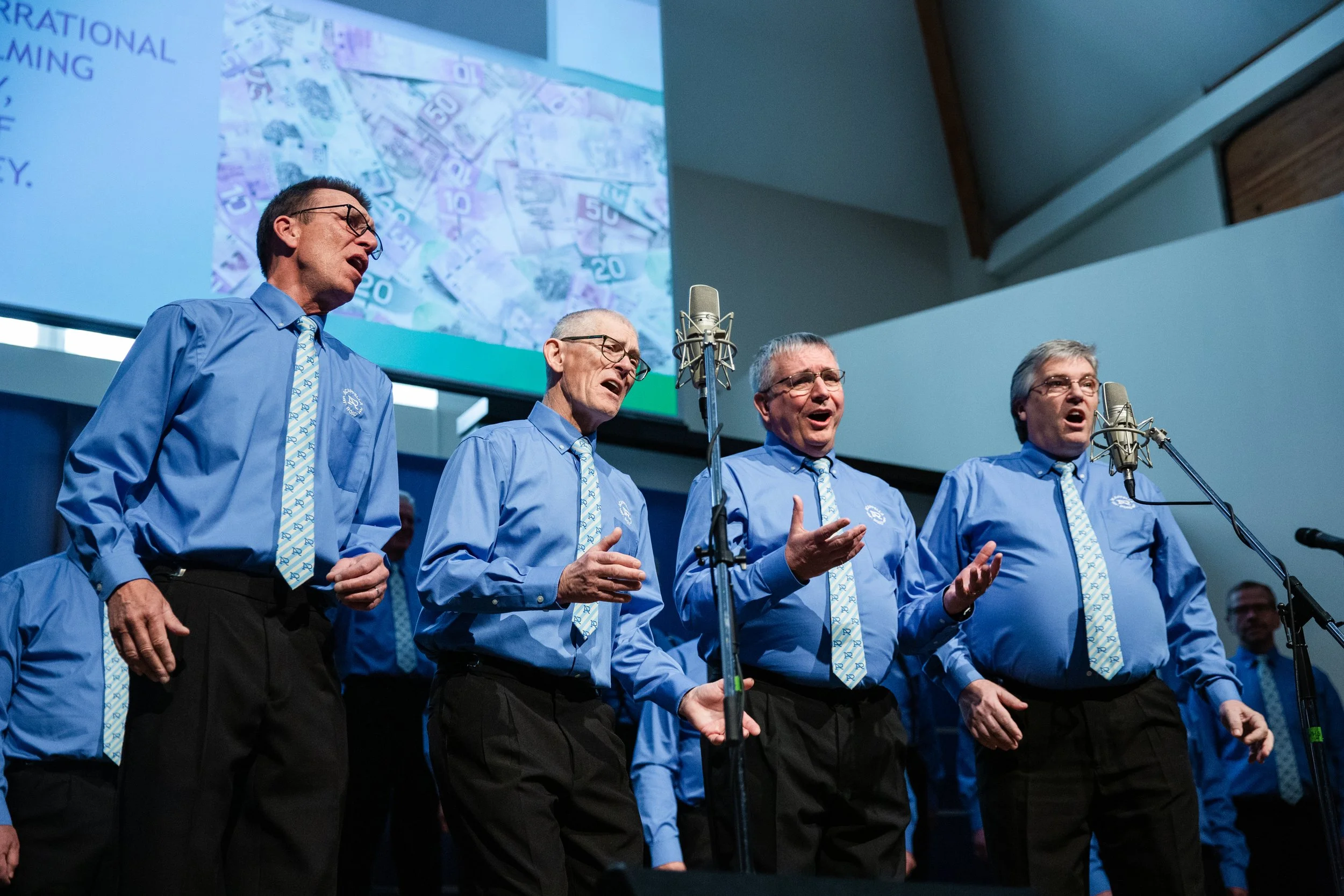 Wicked Pitch of the West, a four-man barbershop quartet, performing onstage in blue shirts and patterned ties.