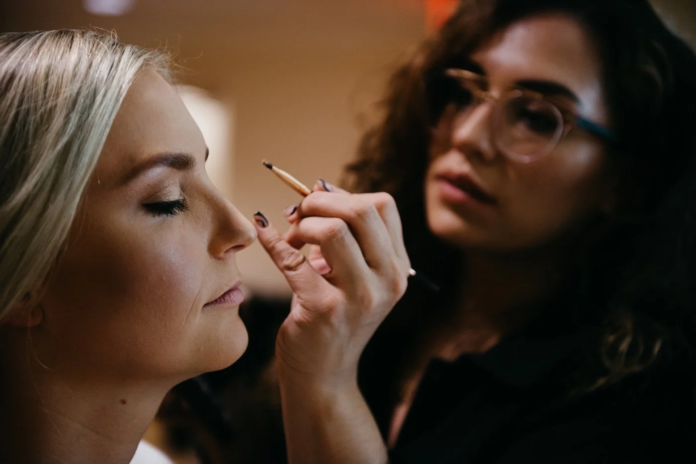 Makeup artist applying makeup to a woman's eyelid in a close-up scene.