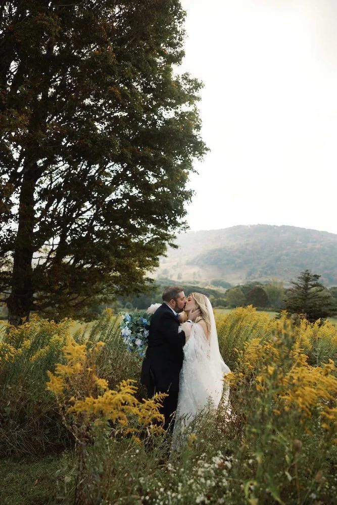 bride and groom kiss in a field of flowers on wedding day