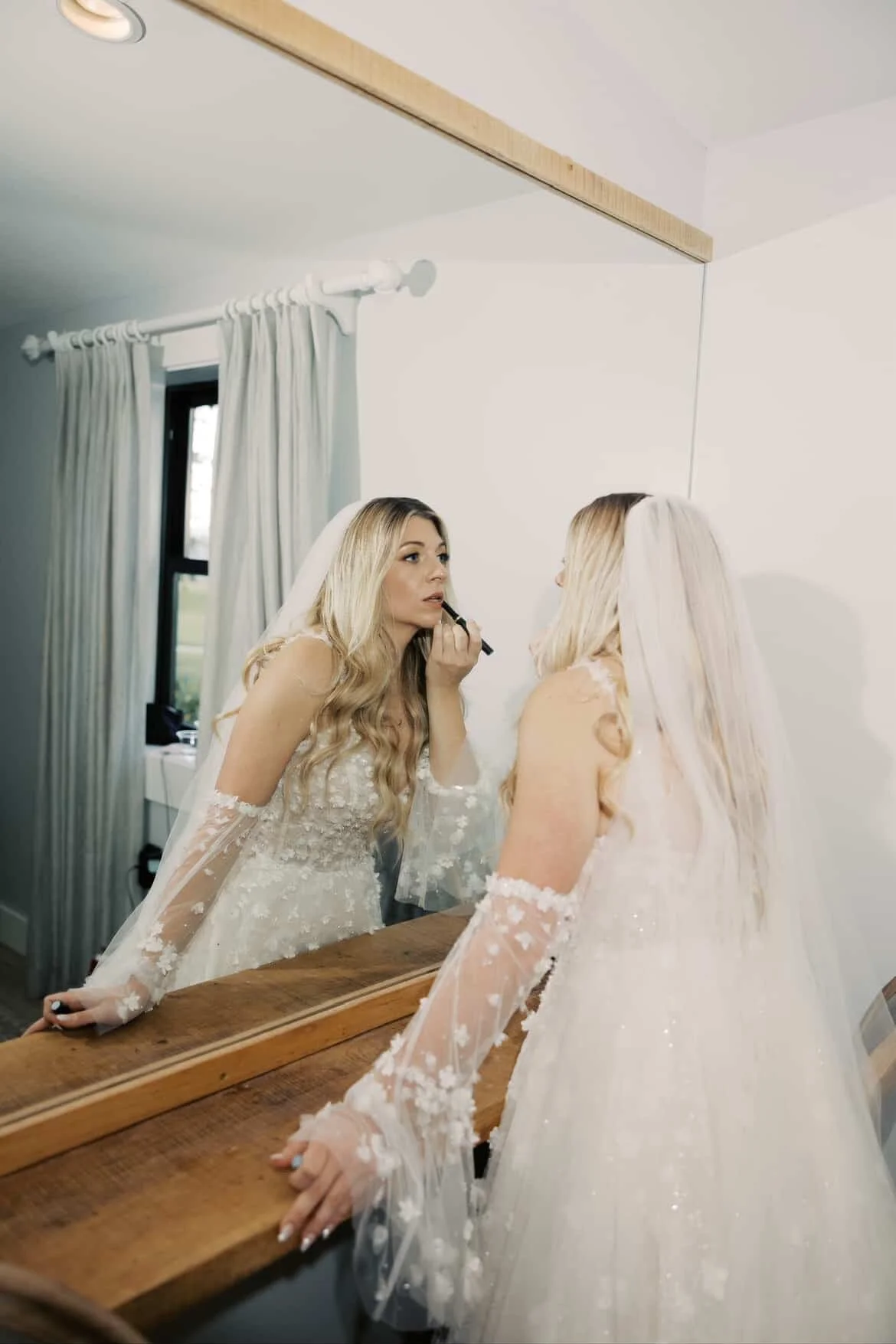 bride putting on lip stick in the bridal suite before walking down the isle