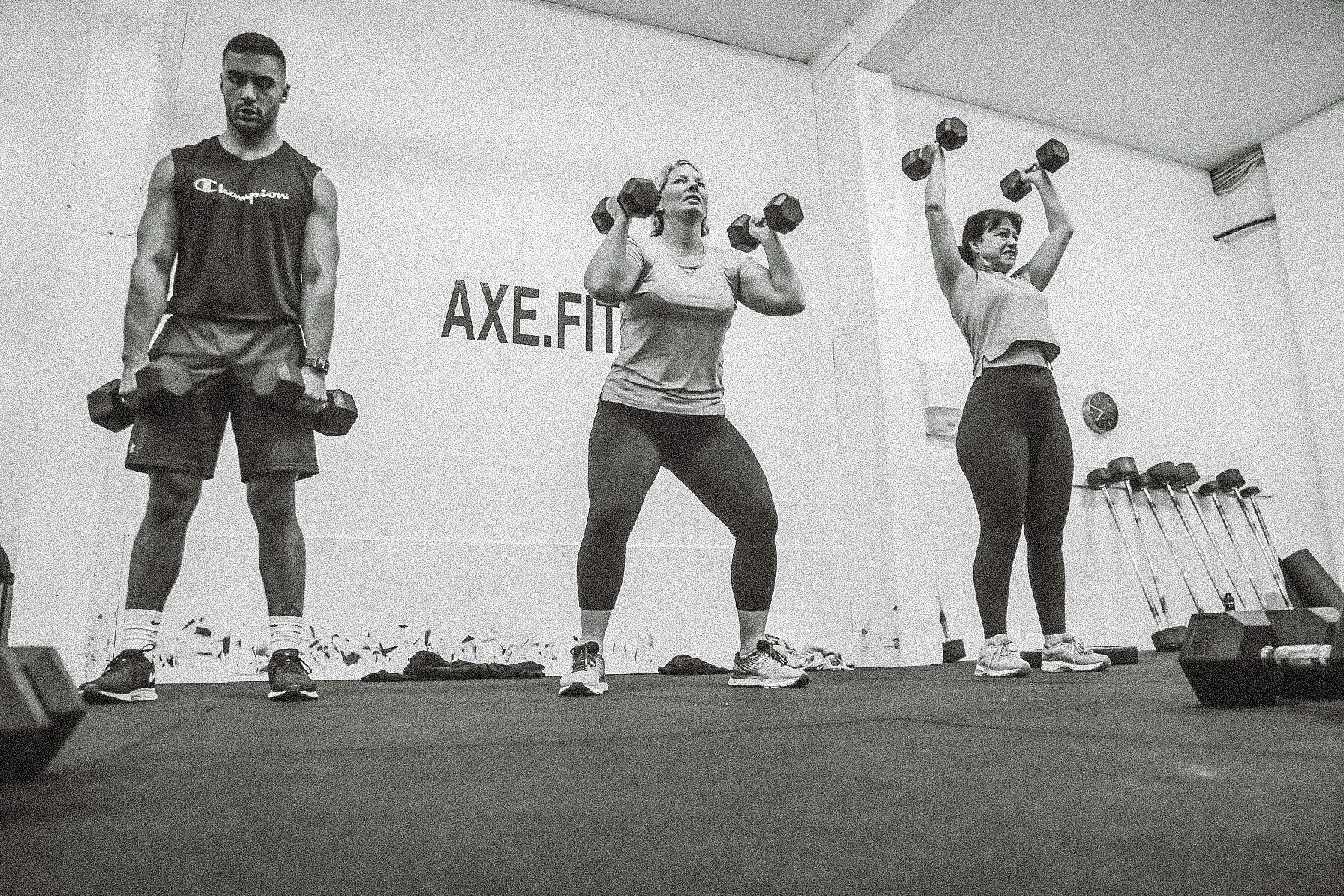 Serious active slim young ethnic female wearing green top and dark leggings looking at camera on light grey background