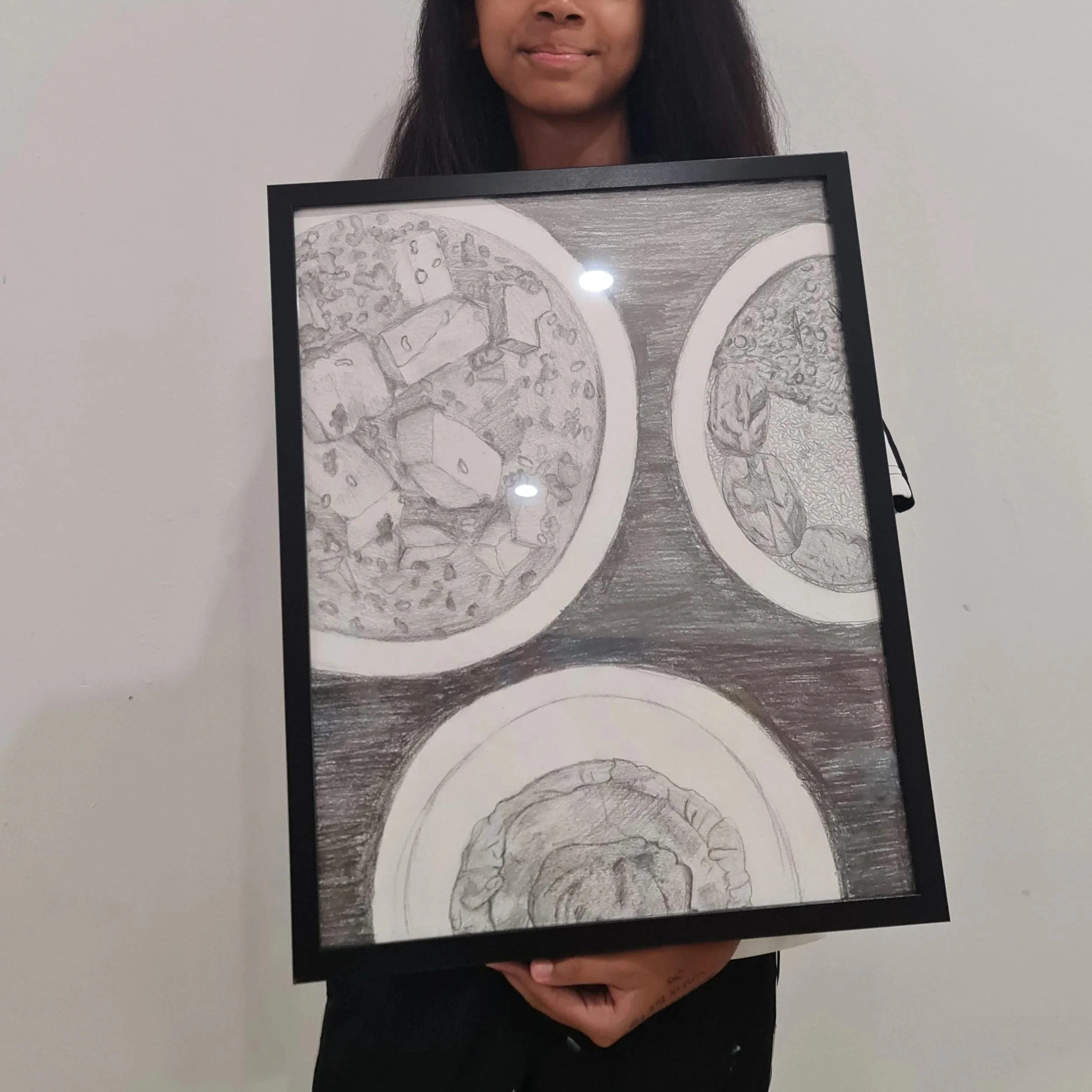 A person holding a framed pencil sketch of pizza slices on a white background.