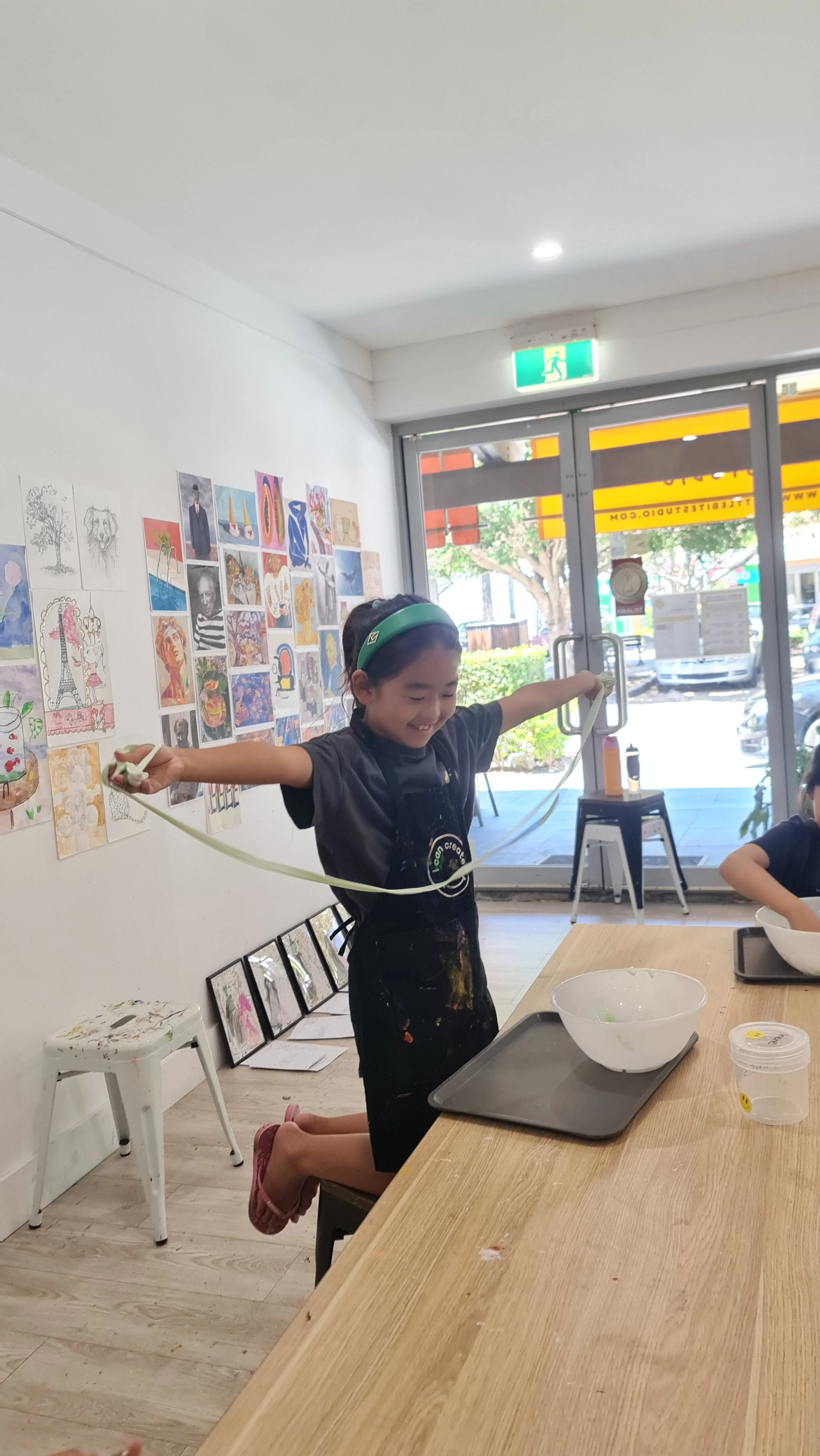 Children mixing green slime and painting Wizard of Oz characters in the Wicked art workshop at A Little Bite Art Studio.