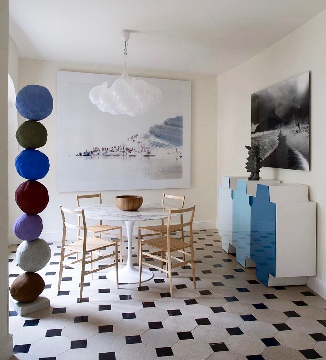 A totem sculpture by Annie Morris makes an impact in a dining area designed by @CSLB_Architecture. An Ugo Rondinone sculpture sits atop a Galerie Kreo sideboard. The chairs surrounding the Eero Saarinen Tulip table are by Gio Ponti for Cassina and th