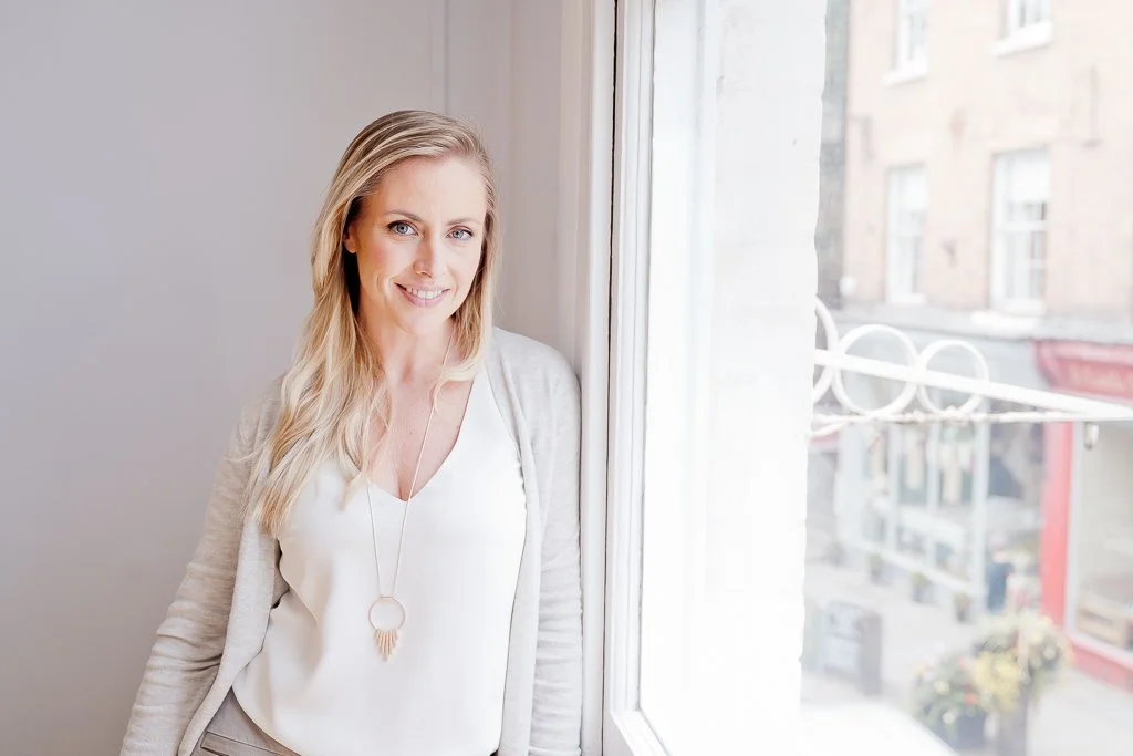 Ally Murphy is standing by a window and smiling.