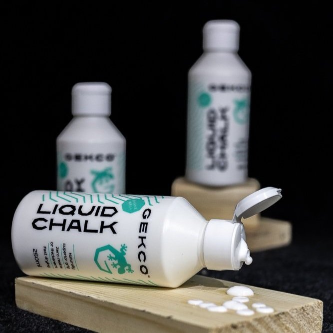 an image of three GEKCO liquid chalk bottles displayed on pieces of pine planks with one in the foreground knocked over and leaking GEKCO liquid chalk.