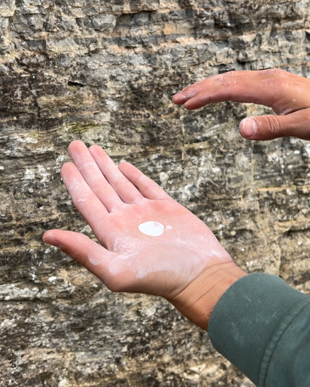Hands about to apply liquid chalk. A squirt of liquid chalk in the palm of the hand at an outdoor crag.