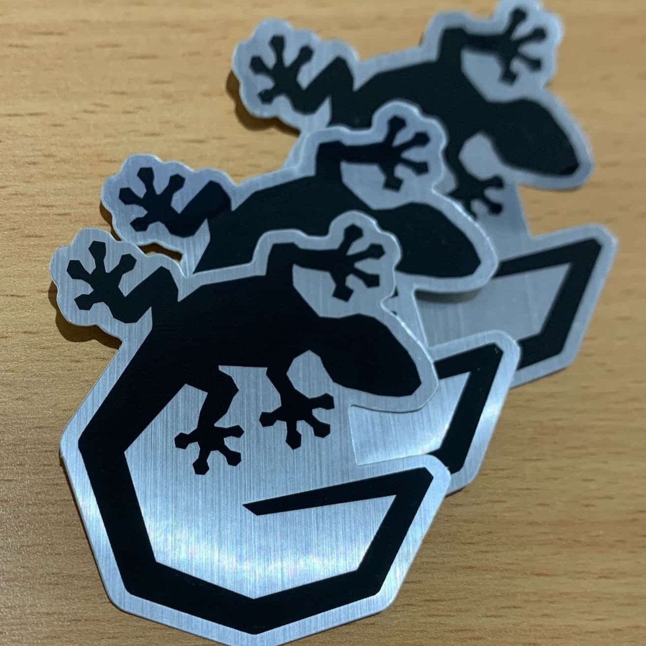 an image of three aluminium stickers of the GEKCO "G" logo in black