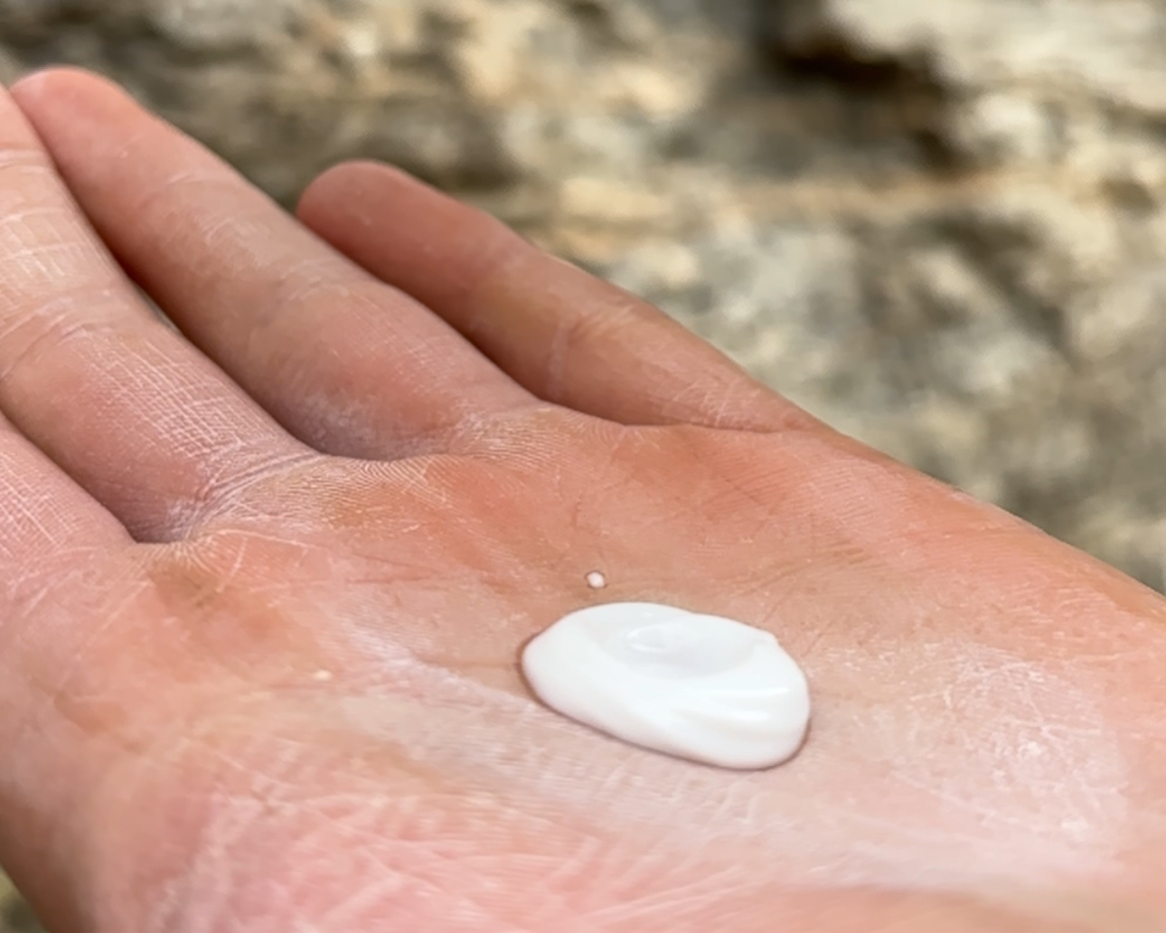 A dollop of liquid chalk on the palm of a climbers hand at an outdoor crag.