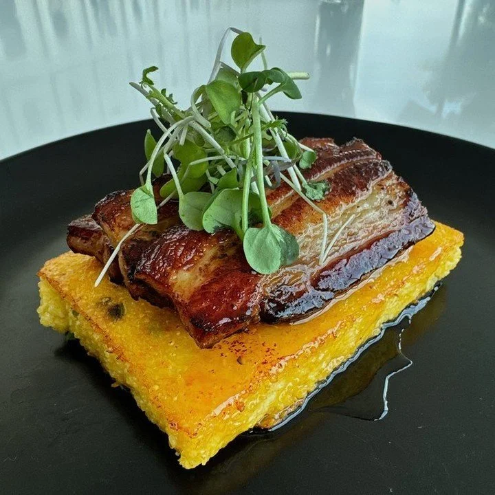 This August, elevate your taste buds with our entr&eacute;e of the month: Pork Belly with Polenta. Tender pork, spicy jalape&ntilde;o cheddar polenta, and a drizzle of hot honey combine for a culinary symphony priced perfectly at $15.