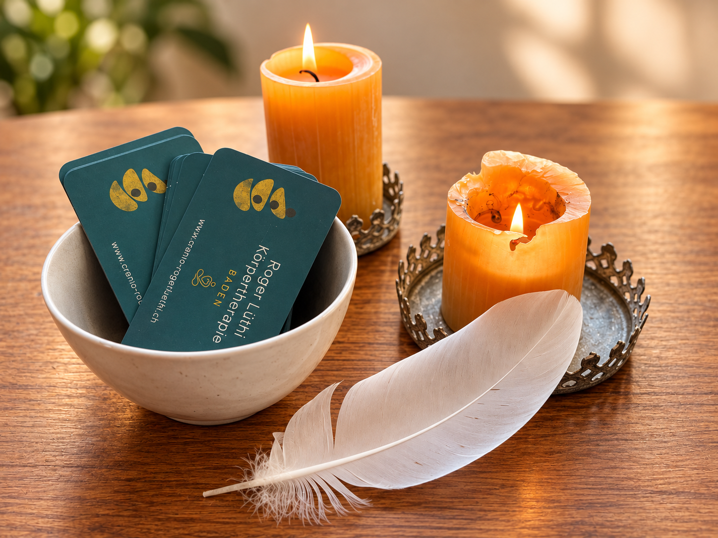 Atmosphäre in der Praxis Roger Lüthi – Körpertherapie in Baden mit Kerzen, Visitenkarten und einer Feder. Ein ruhiger, einladender Rahmen für Craniosacral Therapie und Somatic Experiencing (SE).
