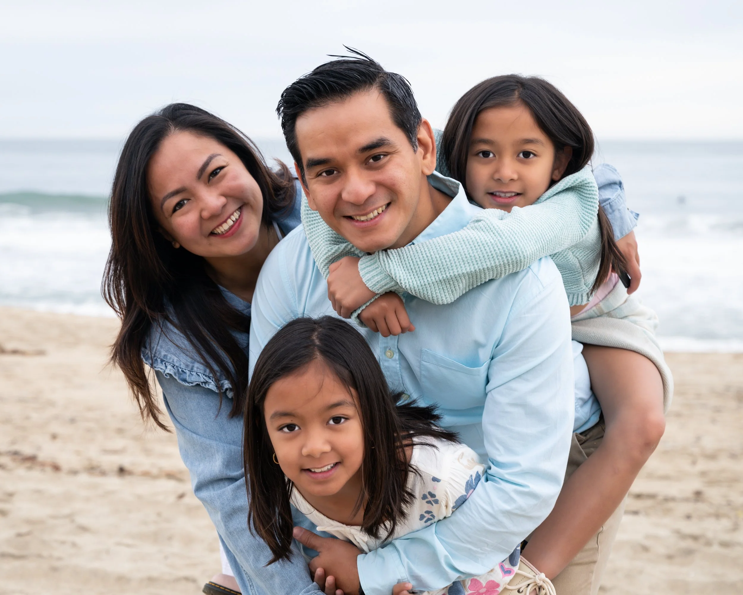 A family of four posing together on the beach during a natural light portrait session at Half Moon Bay.