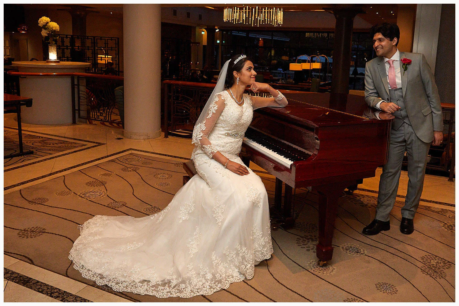 Bride and groom pose for a fun photo with the piano in the foyer of the Village Hotel Caversham Reading