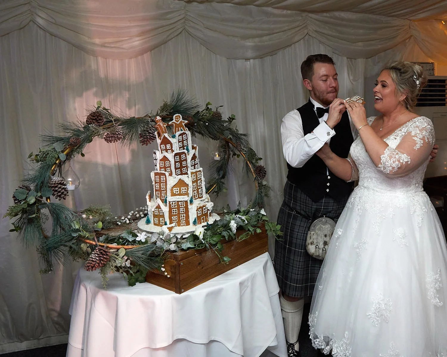 Bride and groom cut their wedding cake at their reception in the marquee at The Mill House Hotel Swallowfield