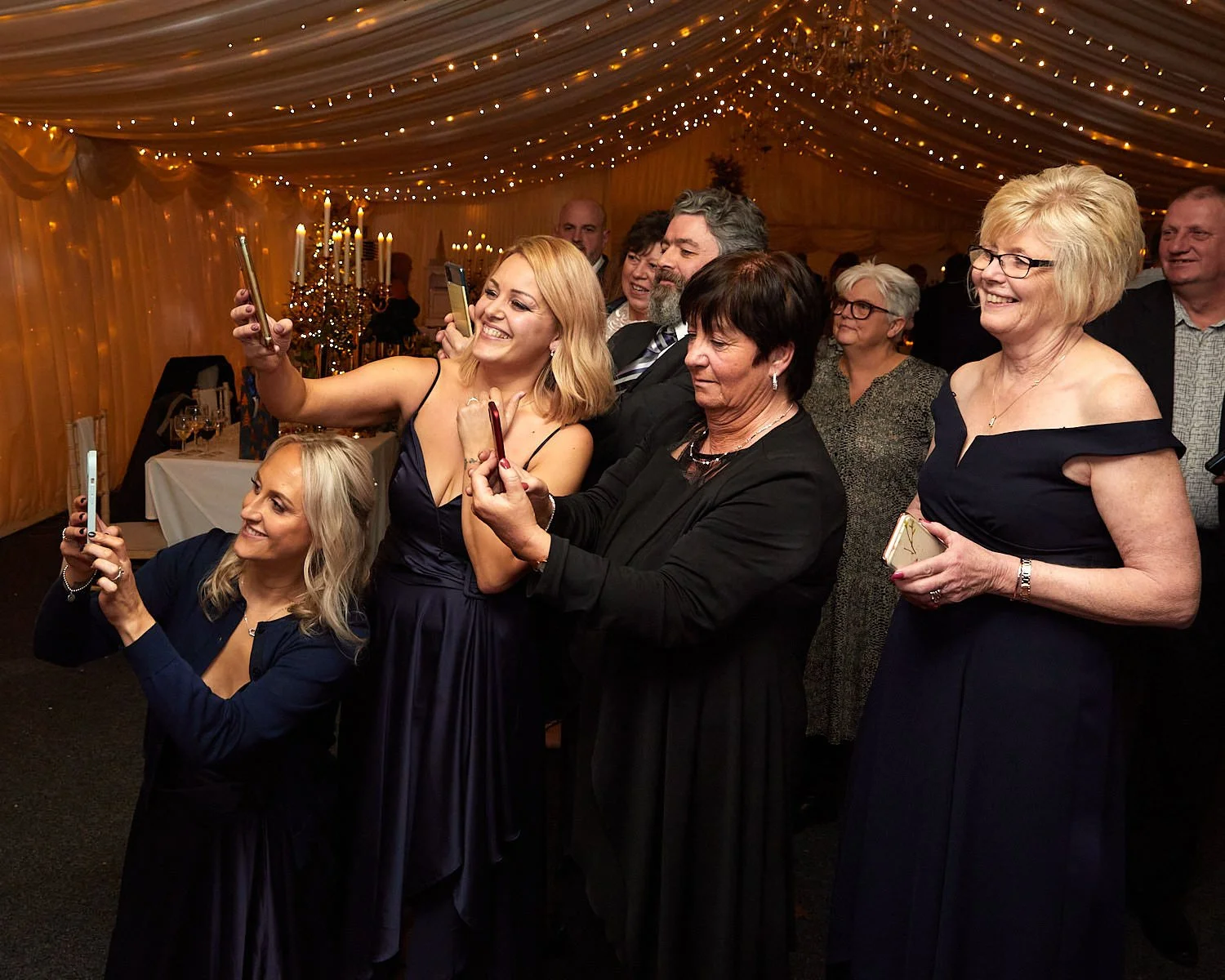 Guests take photos using their smartphones at wedding reception at The Mill House Hotel Swallowfield