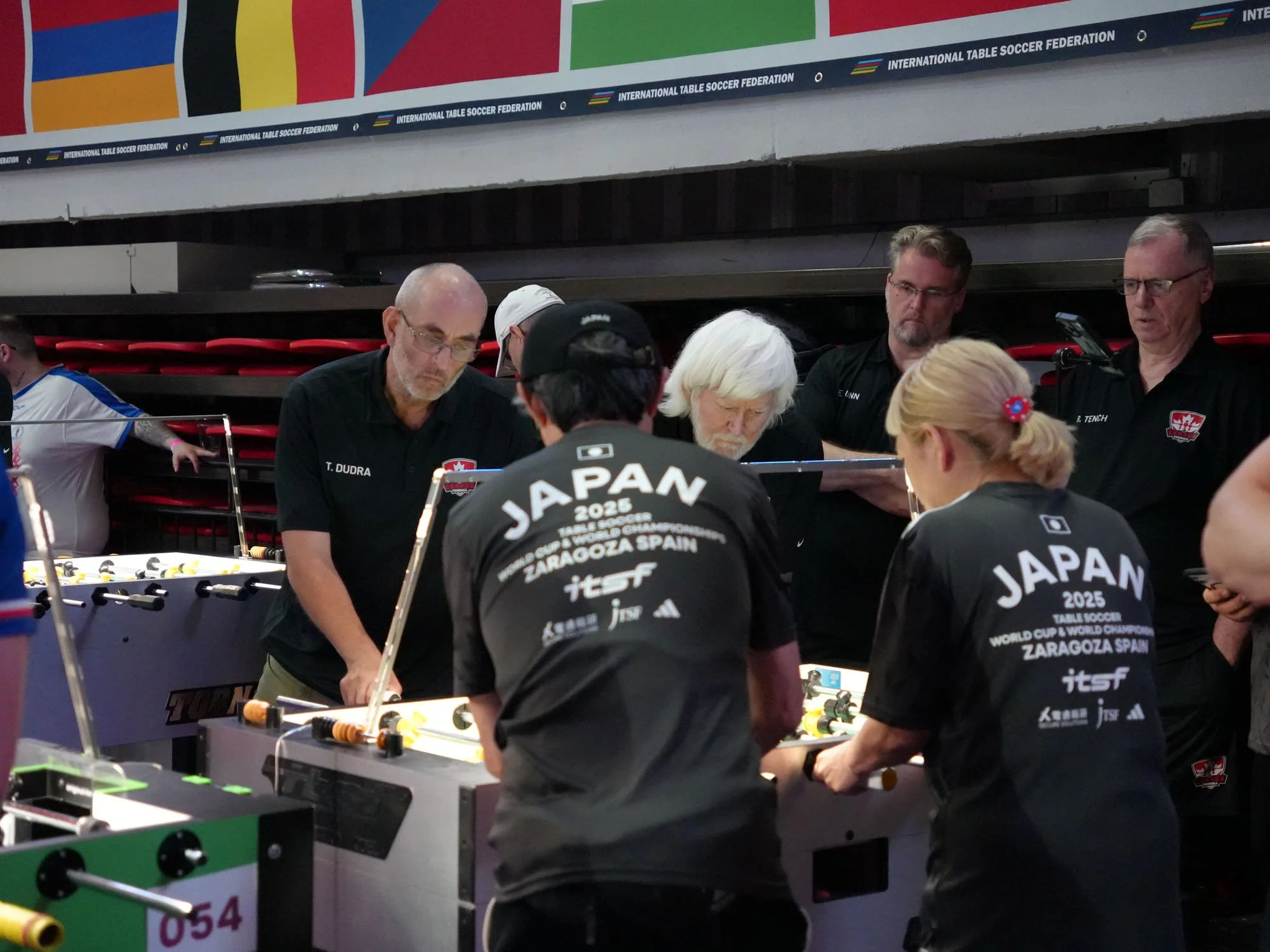 Tim Dudra (left) and Gerry Meister battle Yukiteru Yoshida (left) and Mami Suda as Canada wins Qualification Round 3 over Japan, with Eric Dunn and Richard Tench watching.