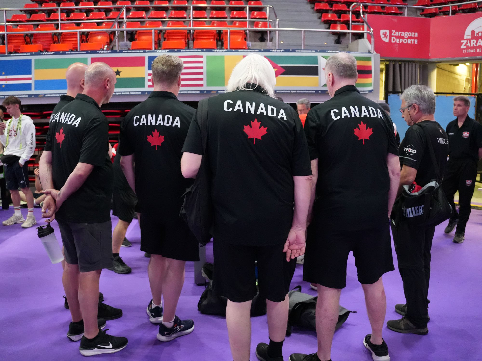 From far left: Canadian Seniors Steve Dumont (obscured), Peter Tielens, Eric Dunn, Gerry Meister, and Richard Tench watch a match.