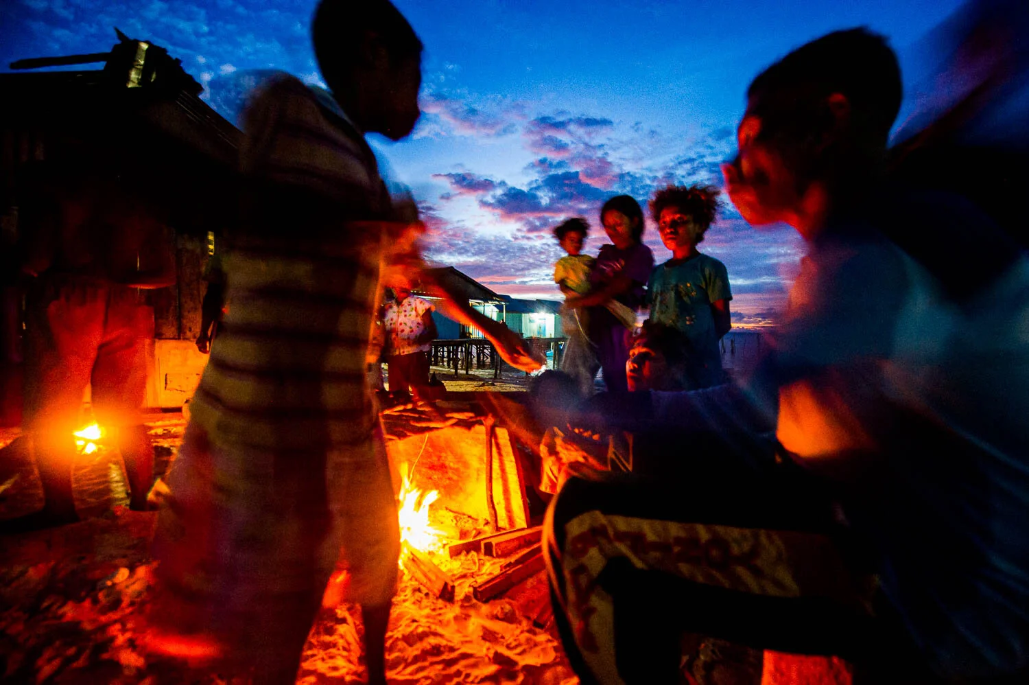 Villagers from Salpele village cook fish on an open fire. A nickel mine across the water will destroy their fishing grounds when it opens. Some residents will be employed by the mine and welcome the move. Others strongly oppose it.