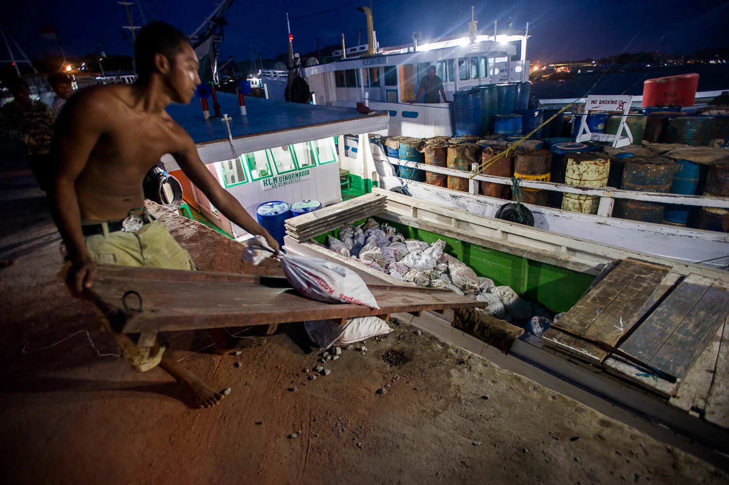 A boat with illegal building materials prepares to leave Sorong harbour for PetroChina, one of the largest Gas and Oil companies. To exploit West Papua's natural resources, the government employed thousands of immigrants from surrounding islands.