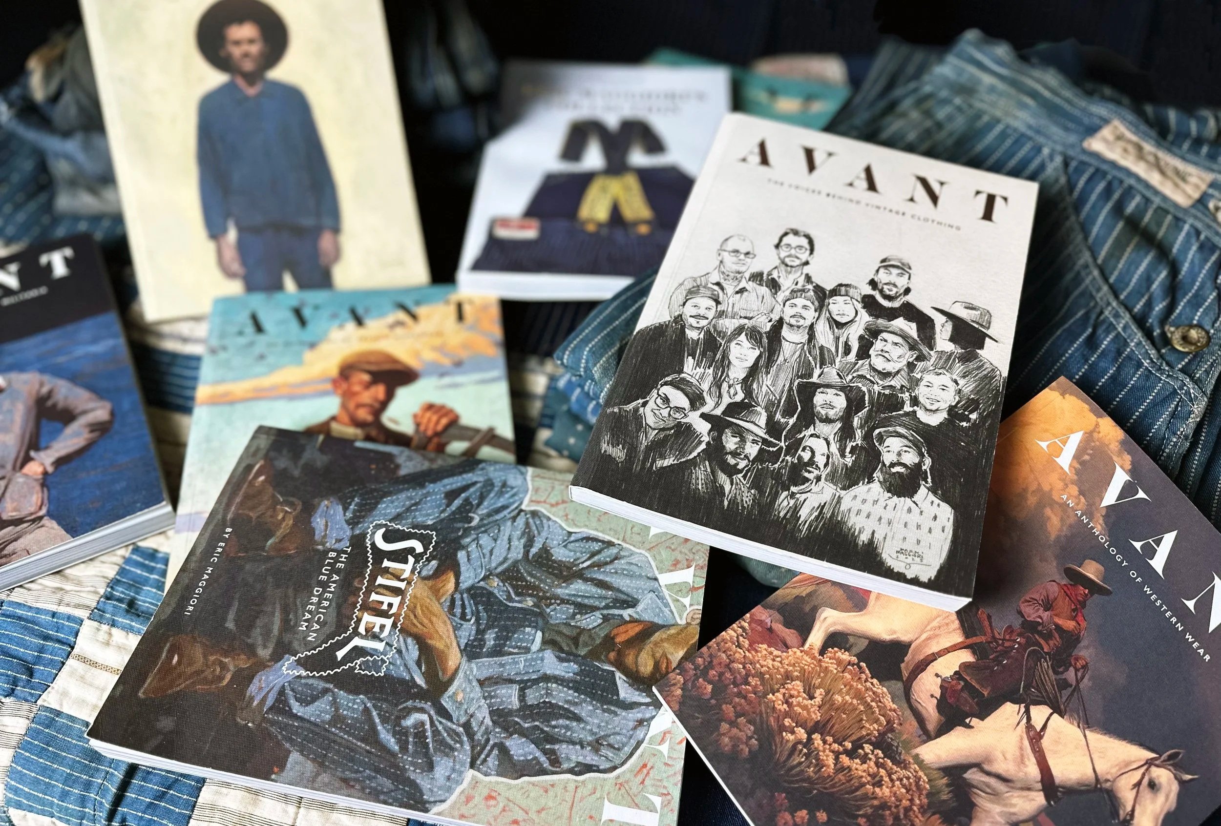A collection of magazines and books with Western and cowboy themes, including illustrations of cowboys, horses, and people in vintage Western attire, spread out on a plaid fabric surface.