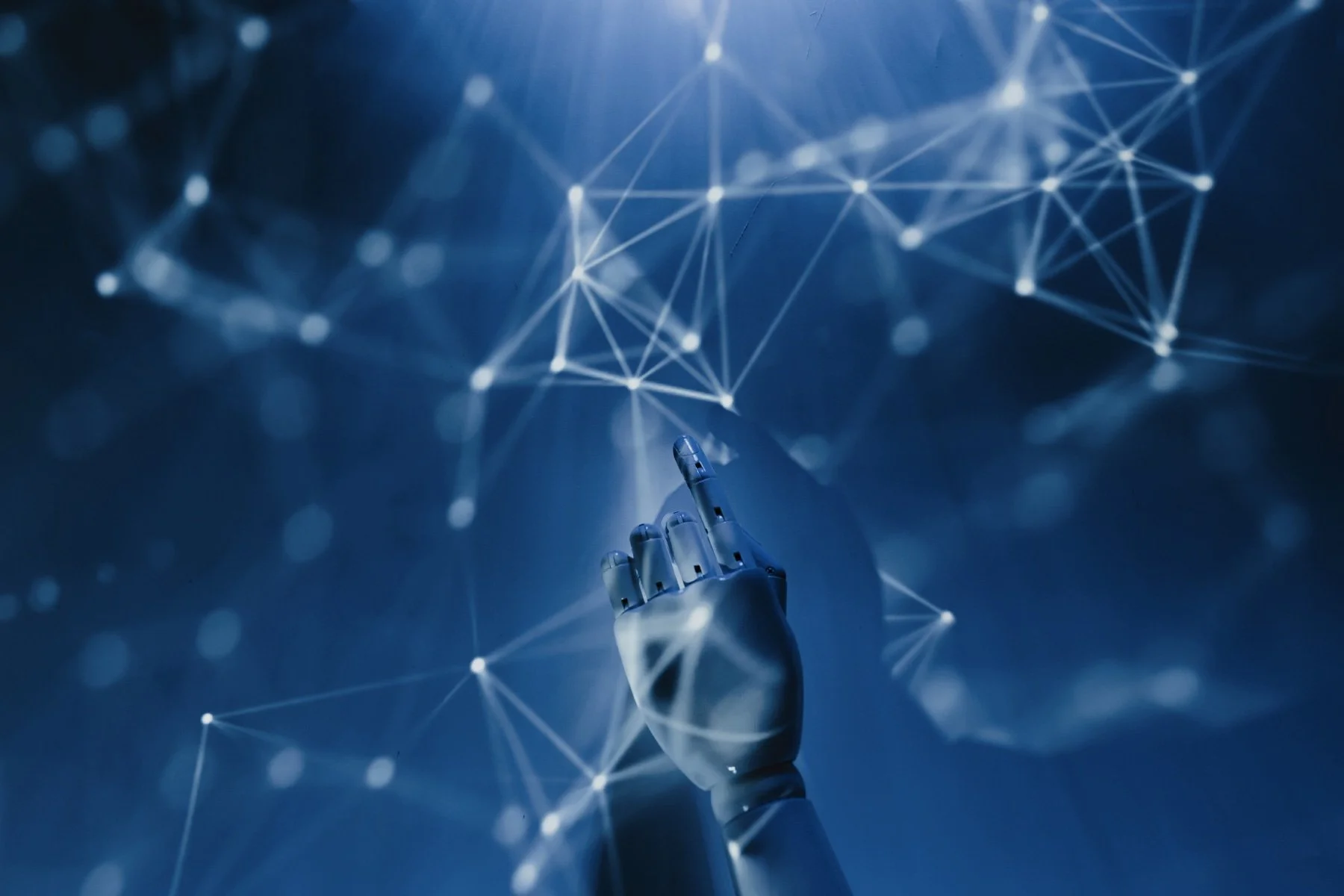 A robotic hand reaching toward a glowing interconnected blue network of light and data