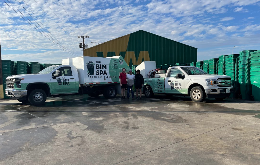 The Bin Spa team posing in front of their trash can cleaning trucks at their garage in Salado Texas from a drone.