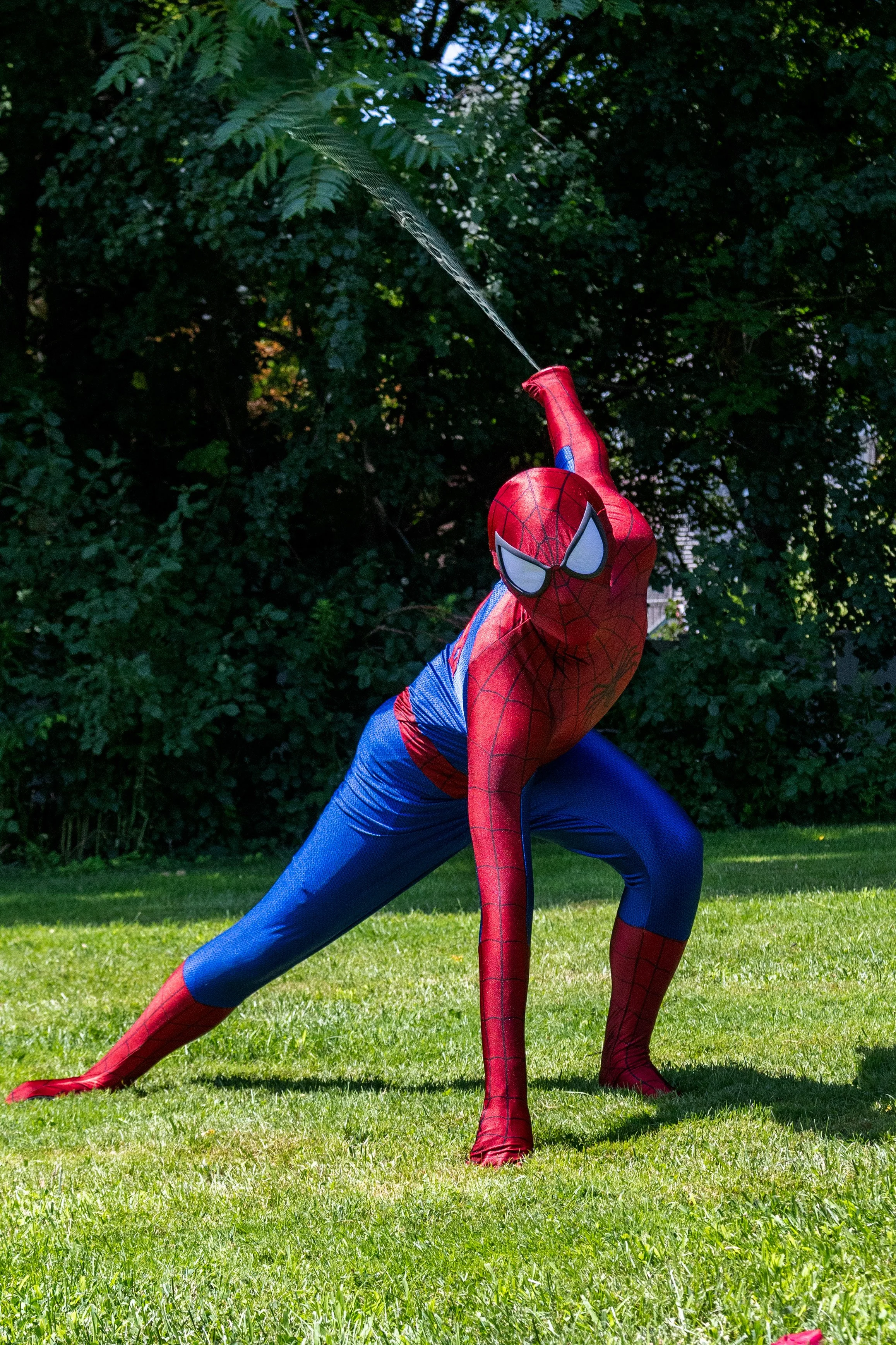 Spider-Hero party character crouching outdoors near a tree with blurred autumn foliage in the background.