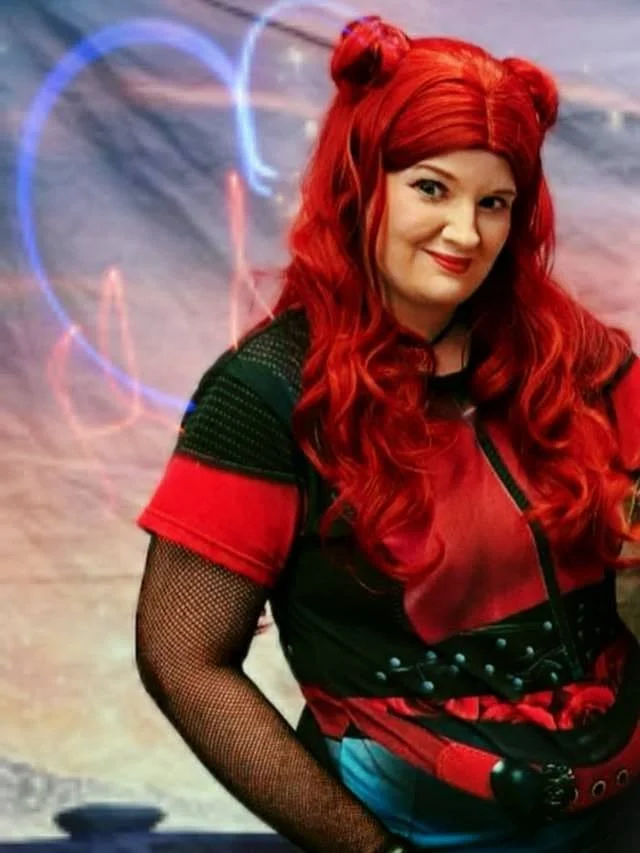 Rebel Teen Villain party character smiling at the camera with flaming heart behind her