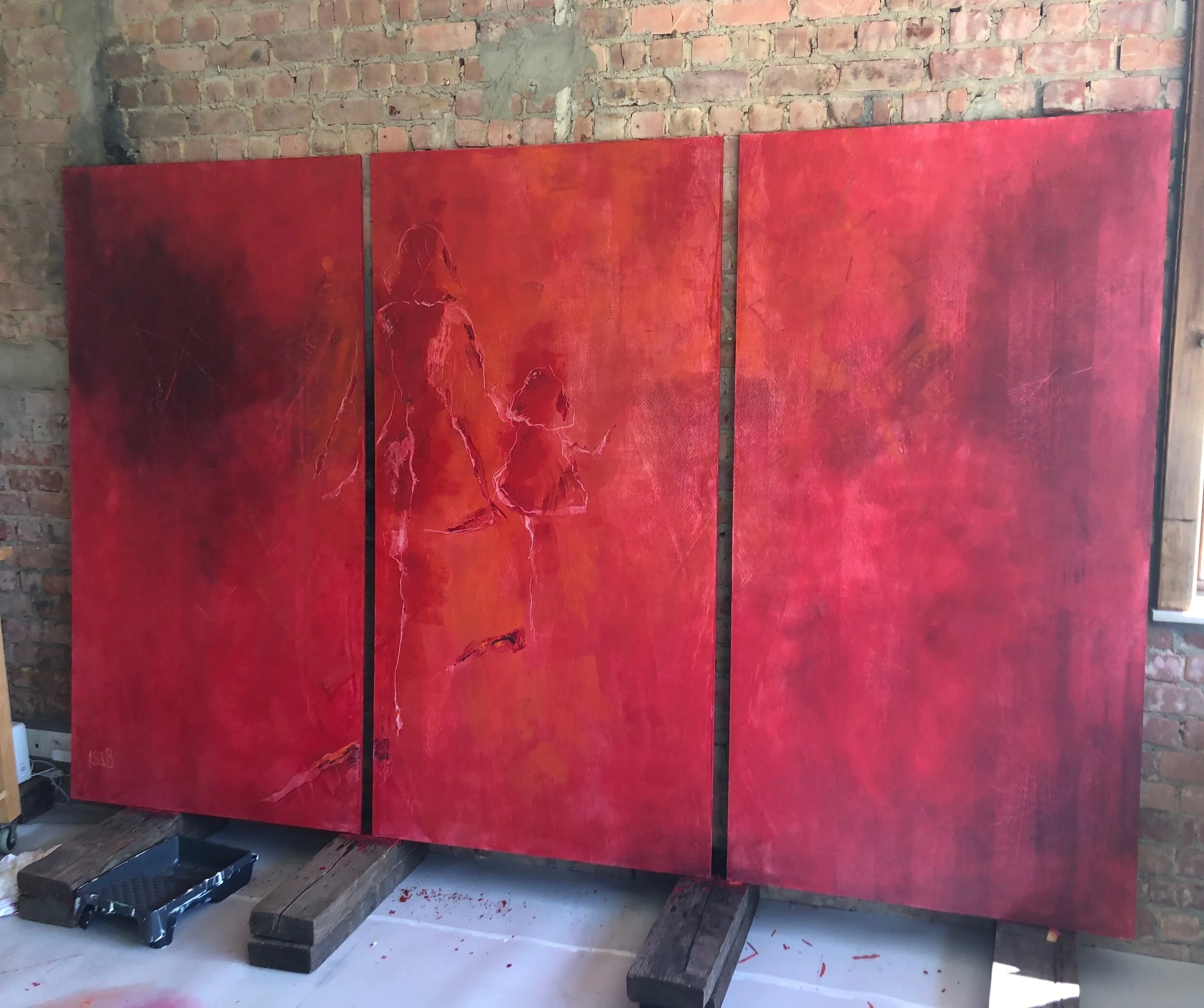 Painting in progress of three red art panels