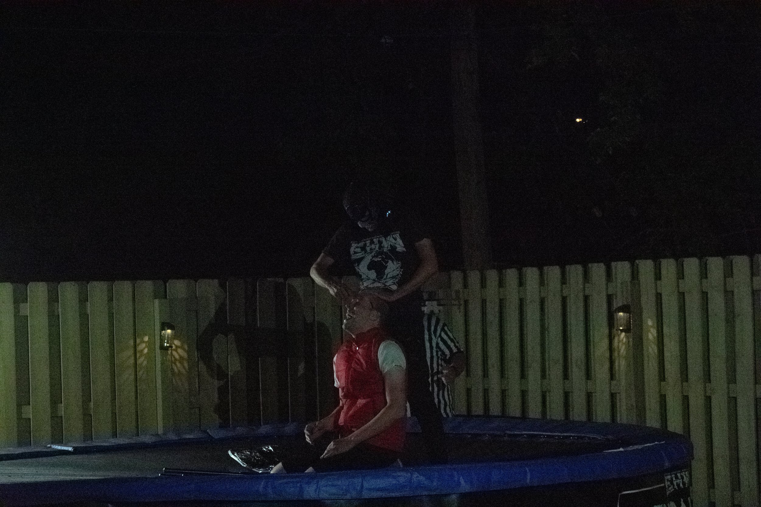 Nighttime wrestling match on a trampoline with a referee.