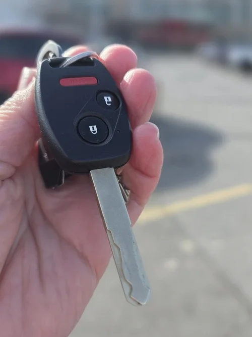 A hand holding a transponder car key fob.