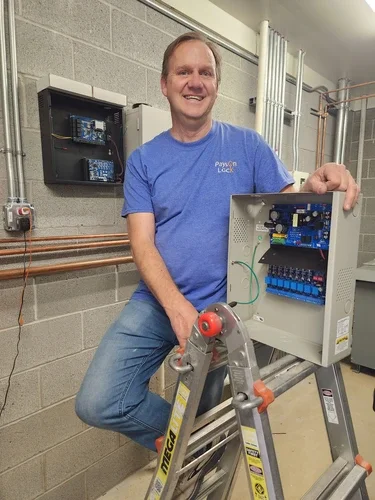 Payson Lock & Key access control technician standing on a ladder next to an electronic access control box in Utah.