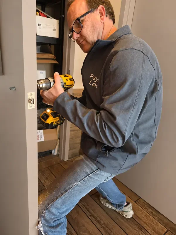 Payson Lock technician drilling a door to install a lock in a retail business.