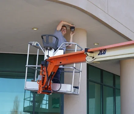 A locksmith installing or repairing a cctv on a building using a lift.