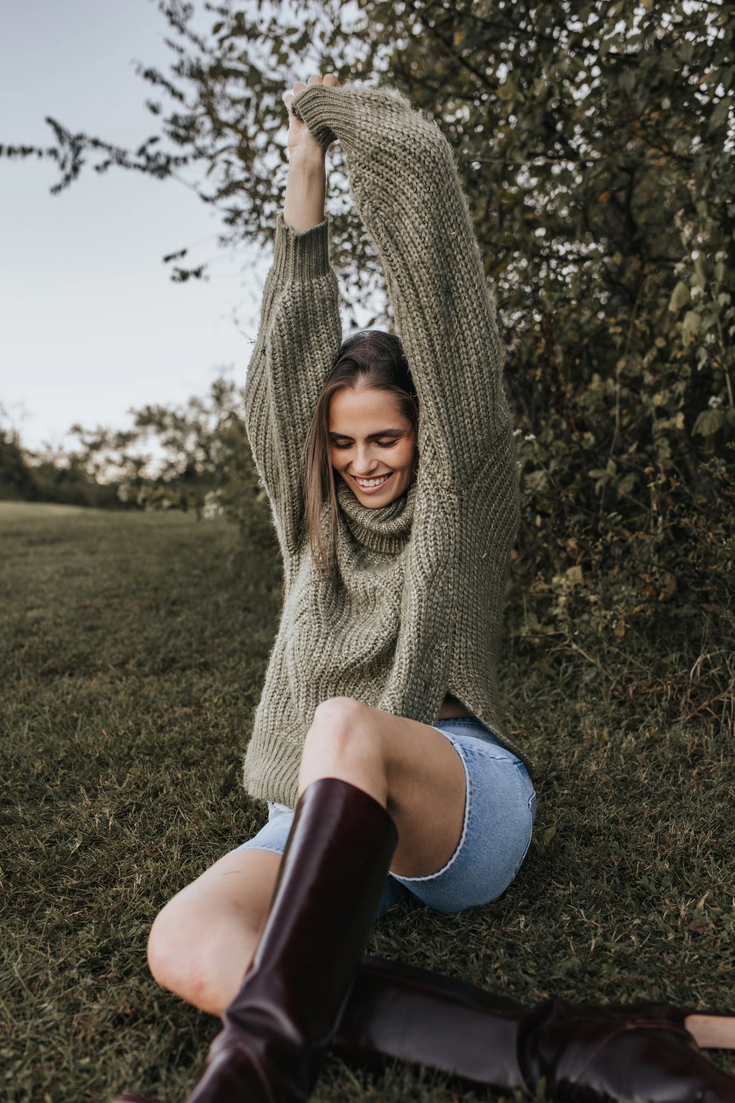  Model Skylar poses in a green sweater, denim shorts, and maroon boots during her Nashville fashion photoshoot. 