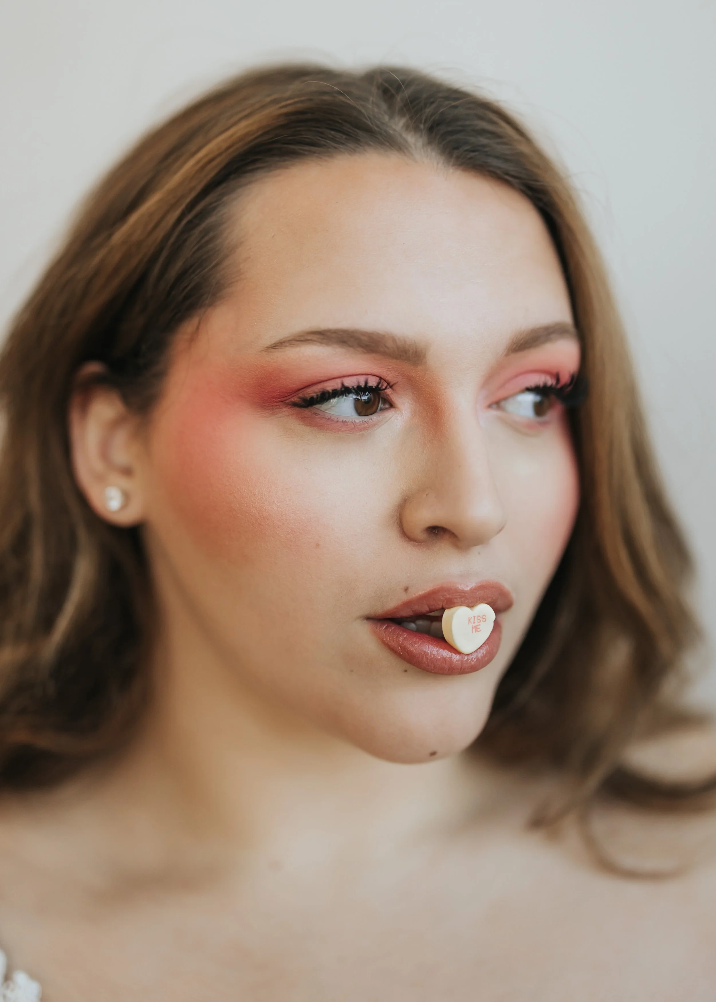 Close up photo of model with candy heart in her mouth for a creative Valentine’s Day fashion photoshoot. 