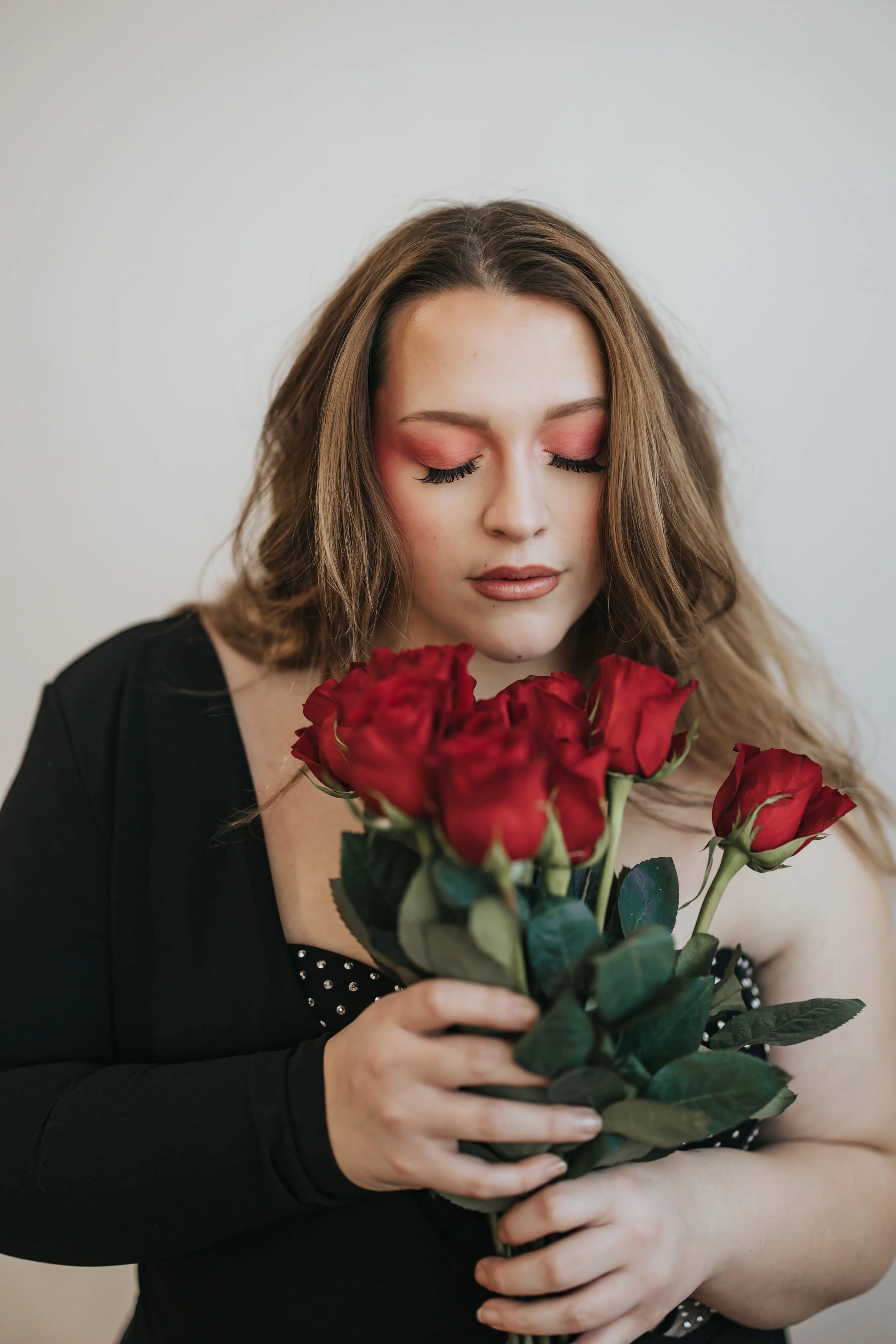  Model poses in a black bodysuit with red roses for a creative Valentine’s Day photoshoot. 
