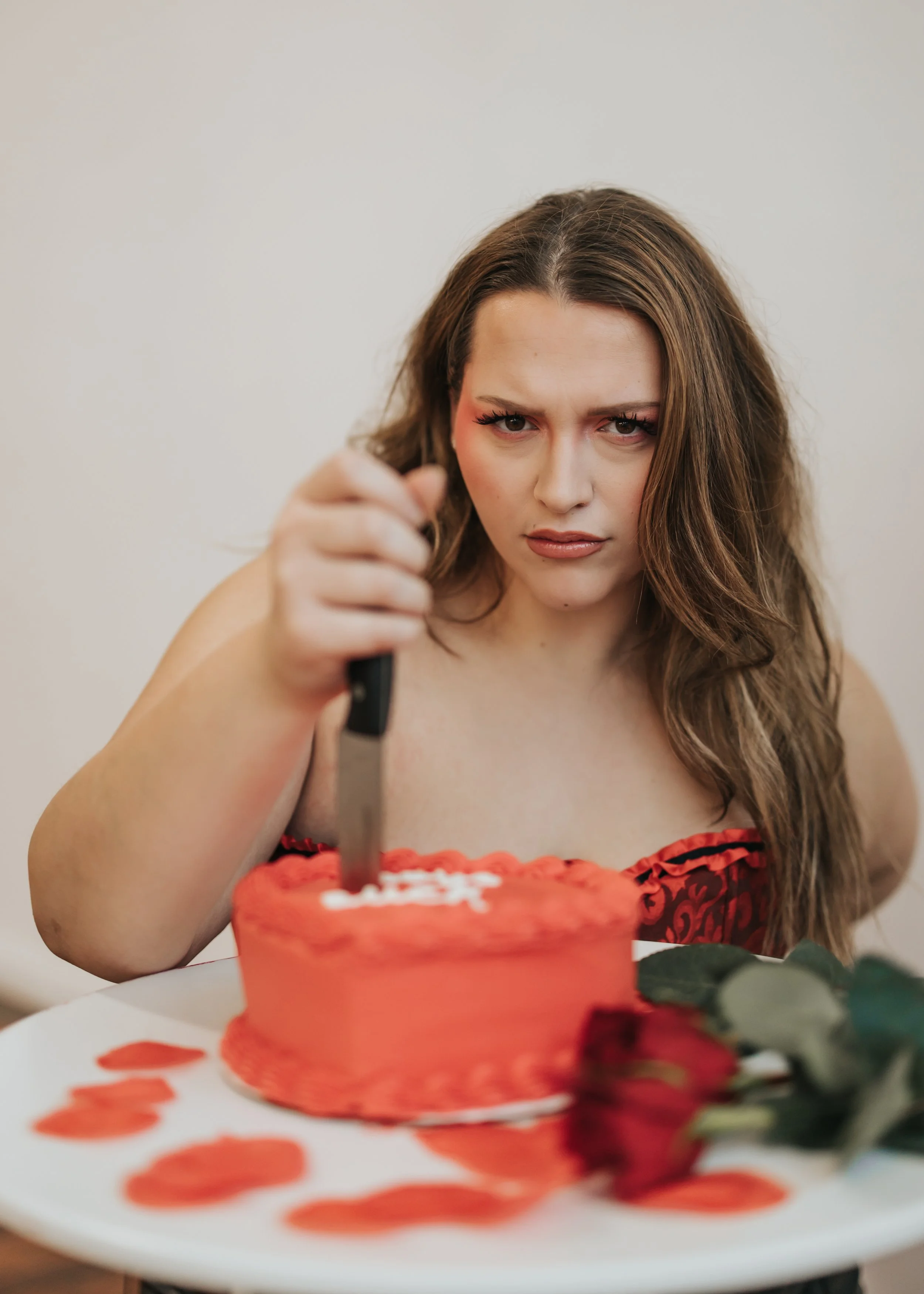  Fashion model poses with a knife in a heart-shaped cake for a creative Valentine’s Day photoshoot. 