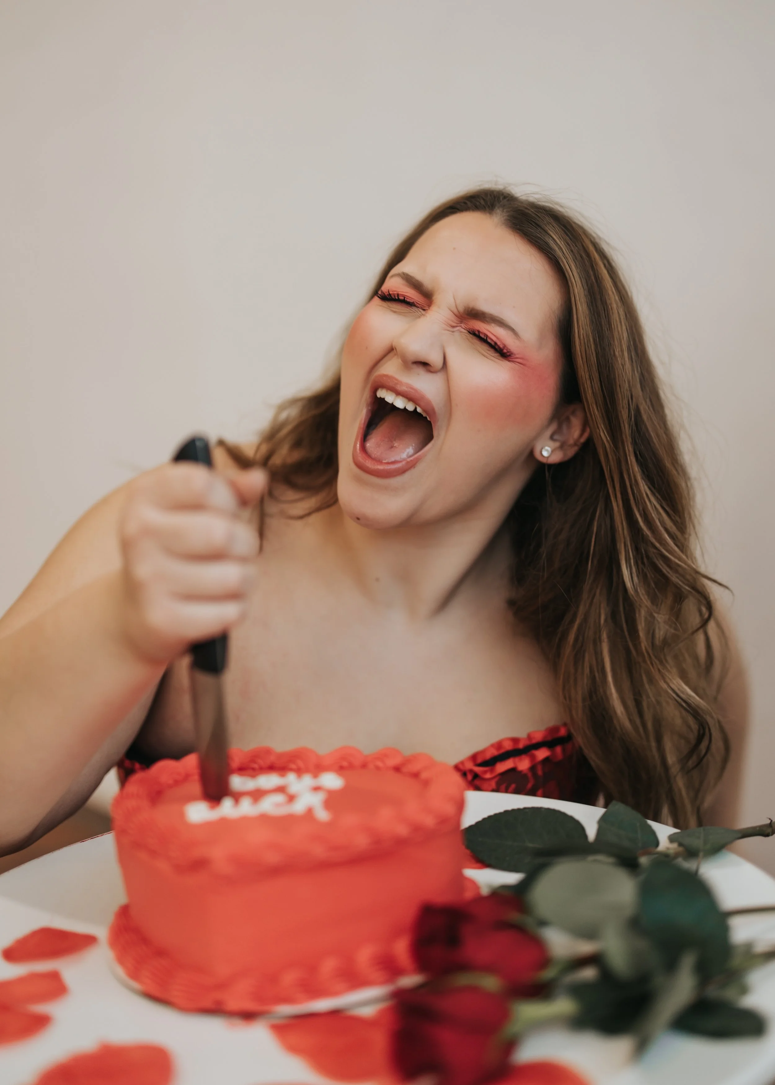  Fashion model poses with an emotional expression while stabbing a knife in a heart-shaped cake for a creative Valentine’s Day photoshoot. 